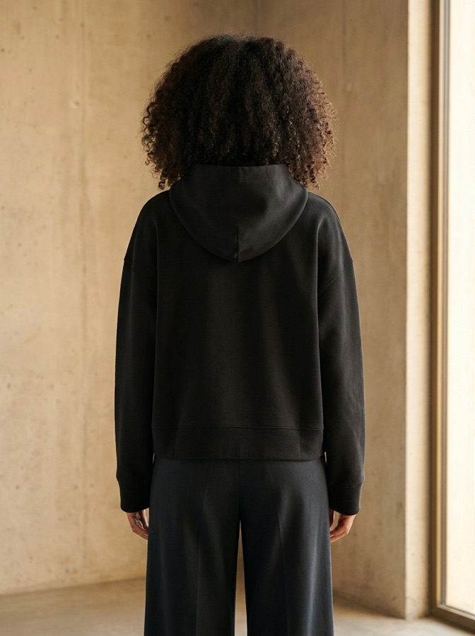 Back view of the black hoodie worn by a model, cross mark centred on the back